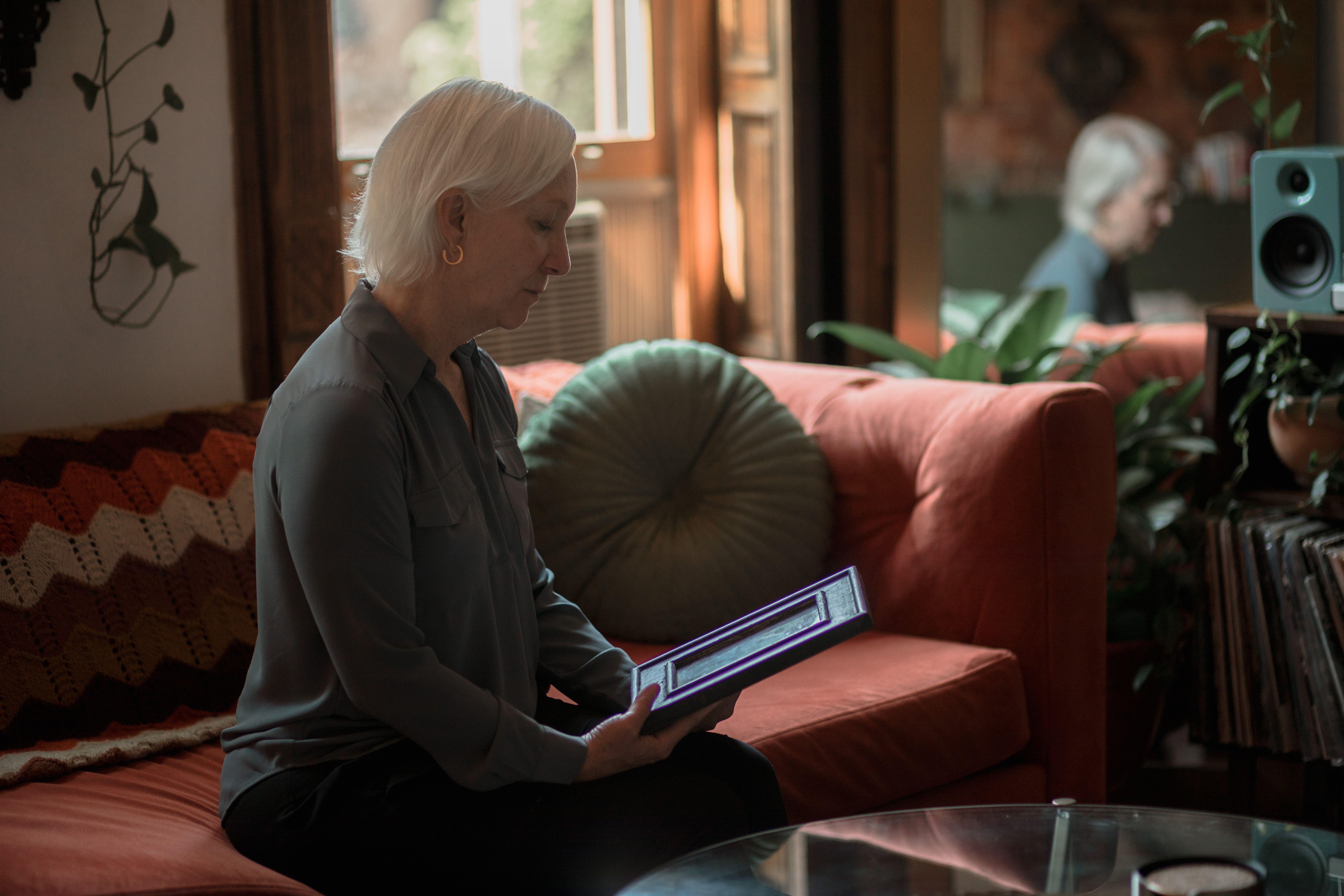 Thoughtful senior woman reminiscing while viewing a photo at home