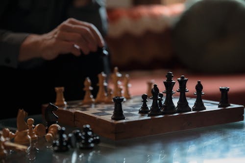 Photo of a Person's Hand Near Chess Pieces