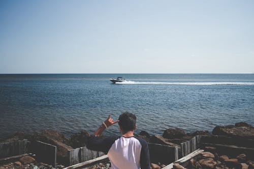 бесплатная мужчина в сине белой футболке рядом с морем Стоковое фото