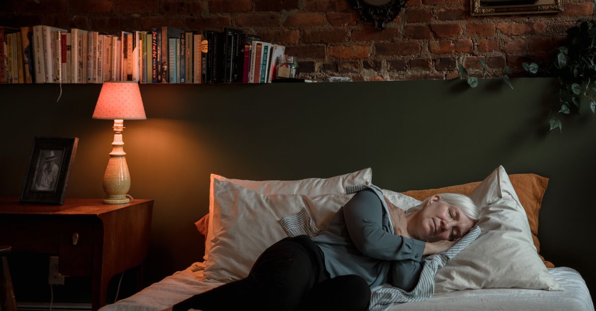 Vrouw slaapt opgerold op haar zij met haar arm onder haar wang