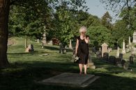 Woman in Black Dress Standing on Green Grass Field