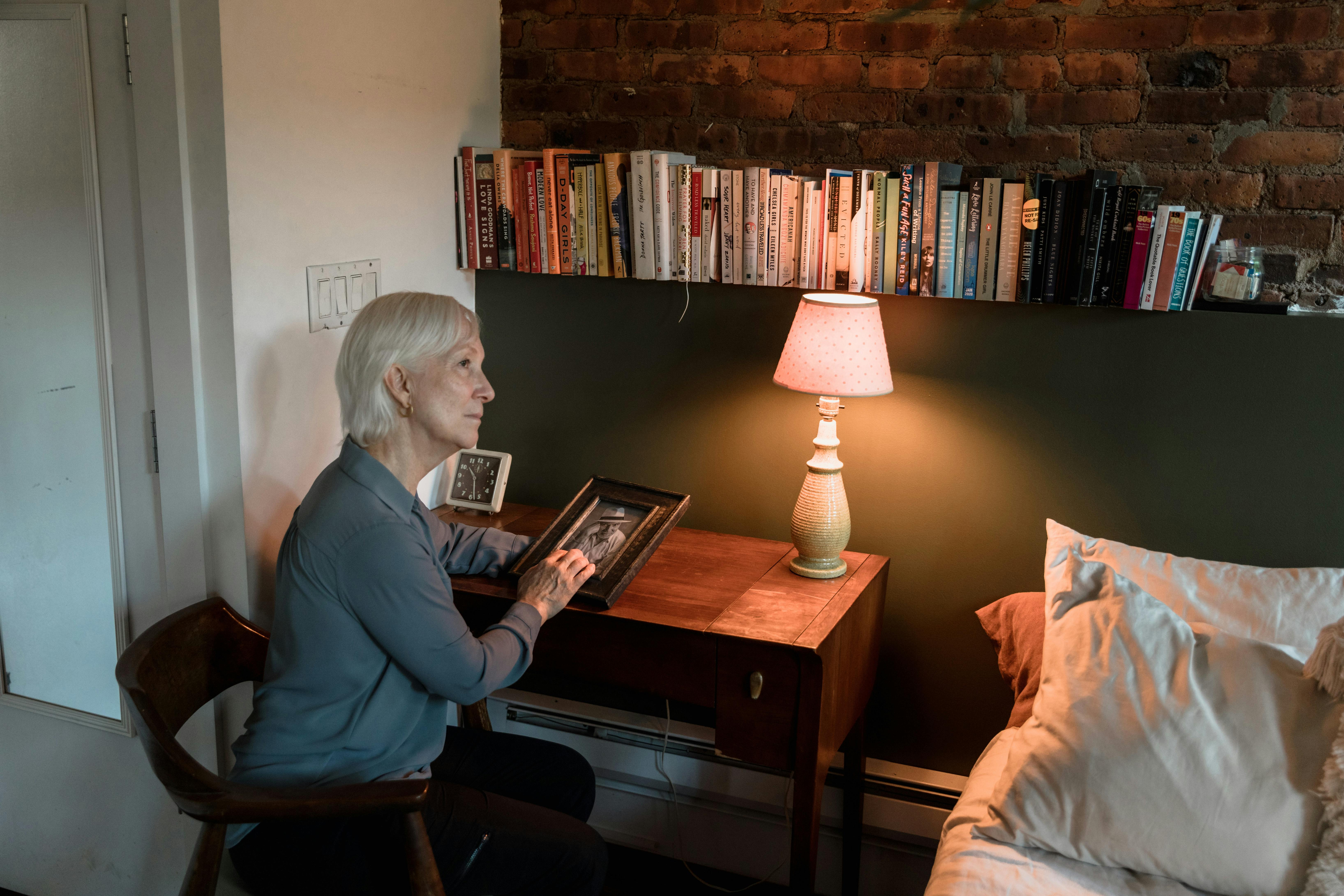 Senior woman sitting in a cozy room, holding a photo remembering loved ones.