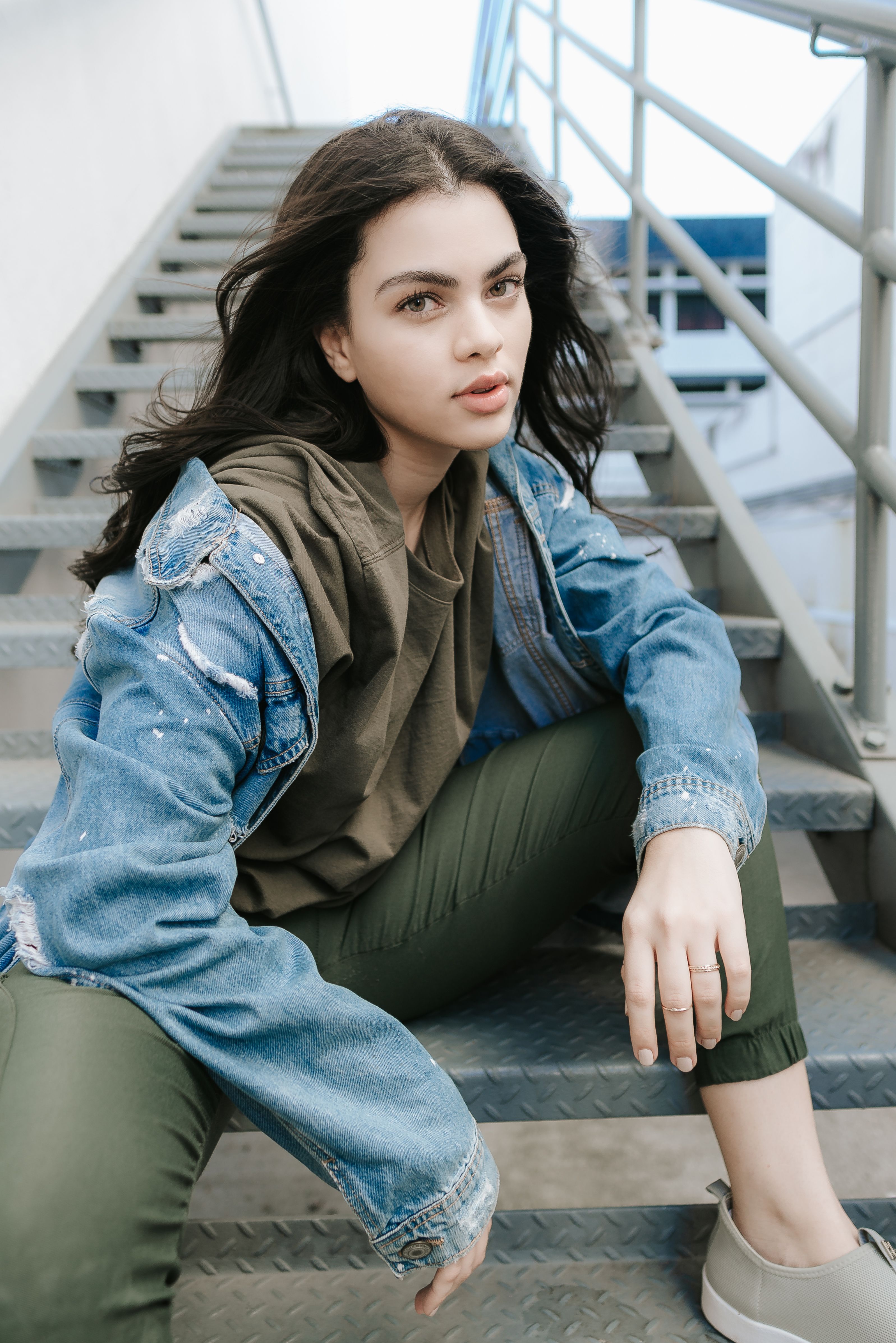 Woman in Blue Denim Jacket Sitting on Metal Stairs · Free Stock Photo