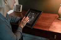 Person in Blue Long Sleeve Shirt Holding Black Wooden Picture Frame