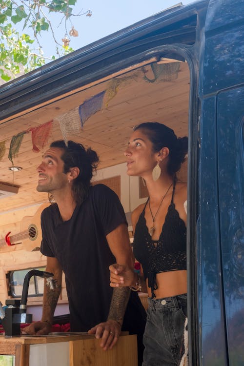 Free A Man and a Woman Standing Inside a Campervan Stock Photo