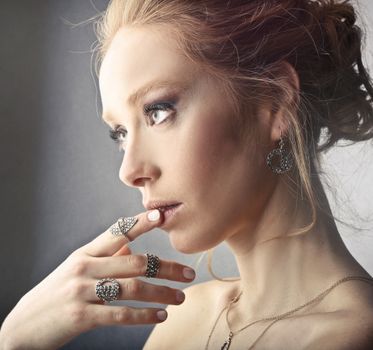 Stylish woman with elegant jewelry admires her reflection, embodying modern beauty.