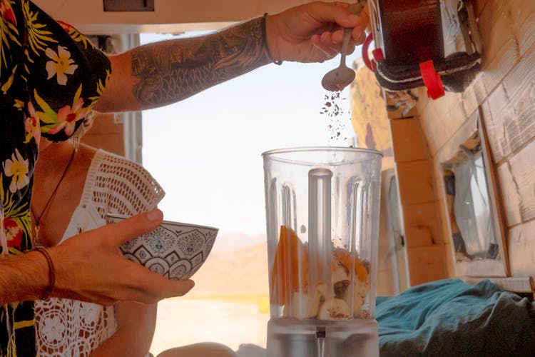 Person Pouring Flakes On A Blender 