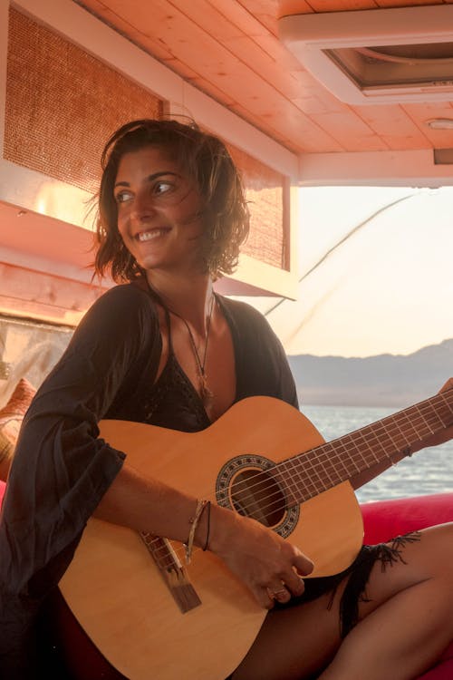 Smiling Woman Holding a Brown Acoustic Guitar