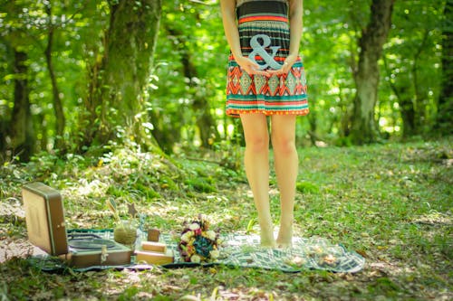 Woman Standing on Picnic Mat Holding Ampersand Lettering