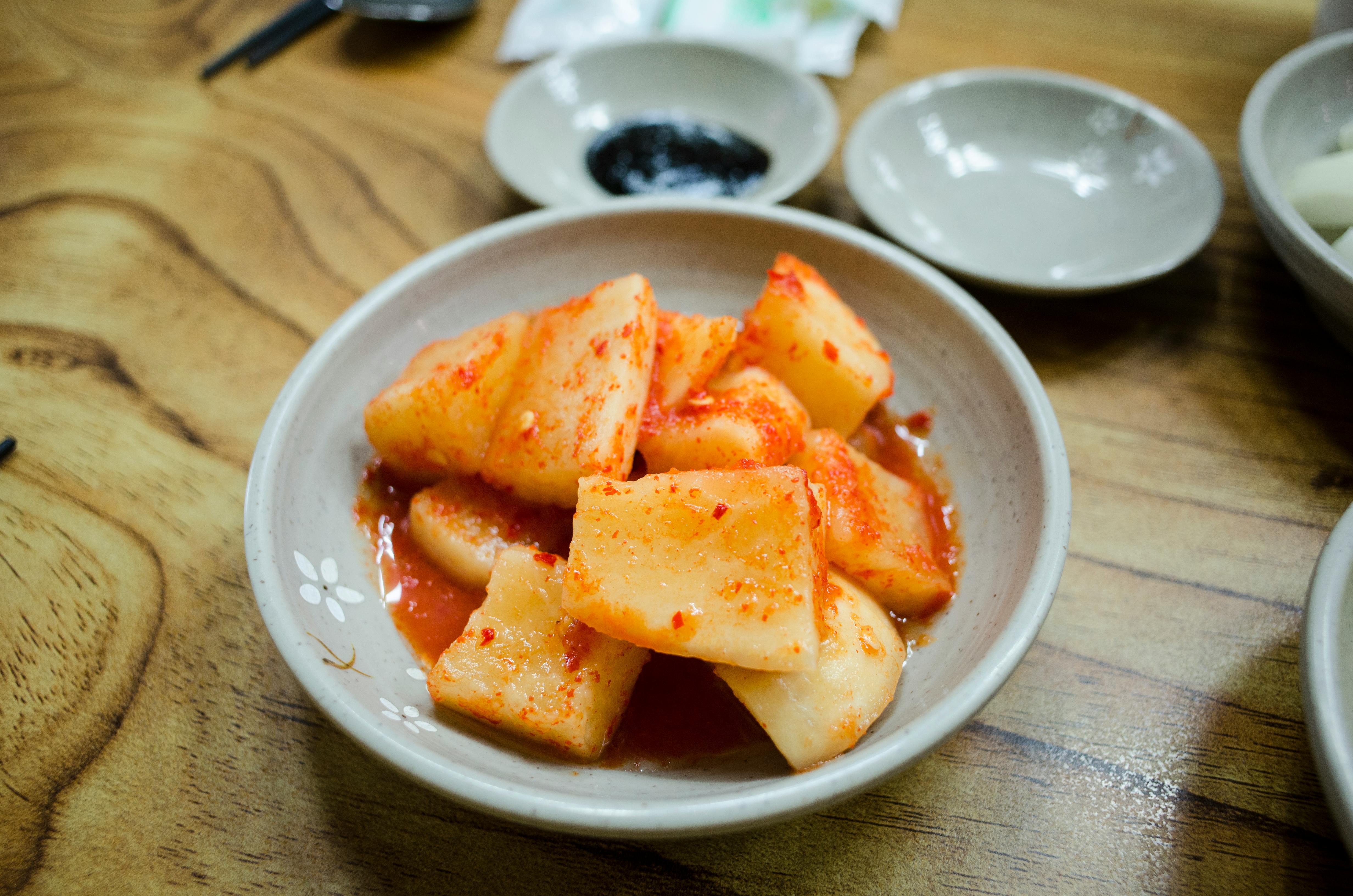 sliced radish kimchi on white ceramic saucer