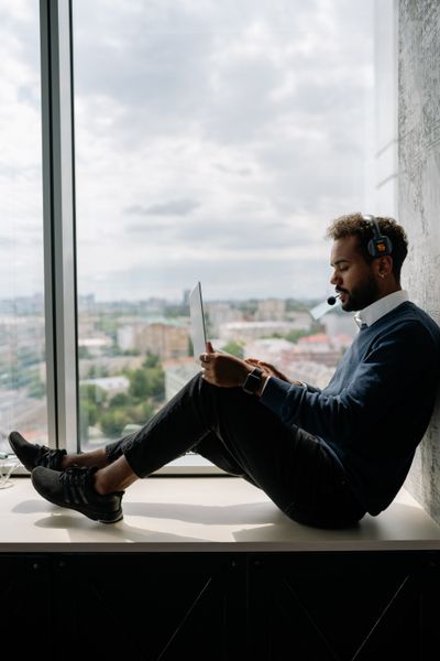 Field engineer working from a window ledge above the city — photo by Yan Krukau on Pexels