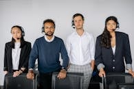 People Wearing Headsets Standing Behind Chairs