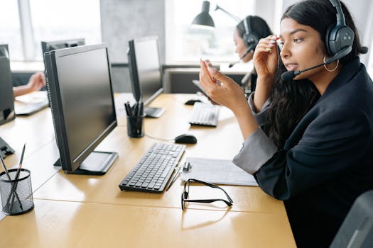 South Asian woman providing customer support in a modern office environment, equipped with a headset.