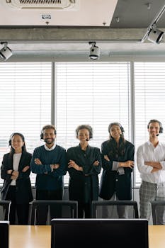 A diverse group of call center professionals with headsets posing confidently in a modern office setting.