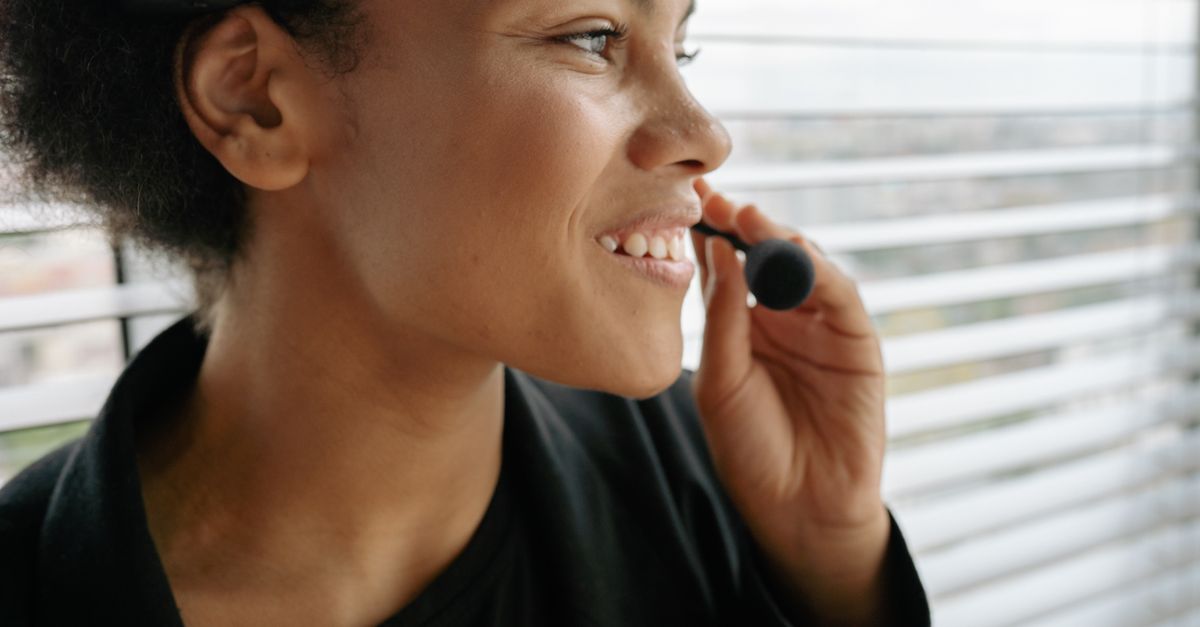 Mujer sonriente atendiendo consultas de clientes con auriculares profesionales
