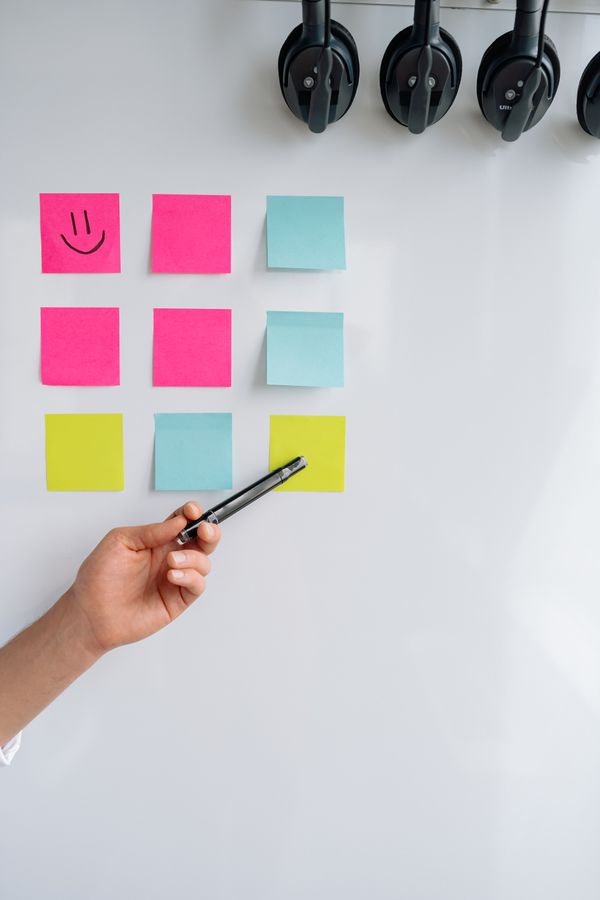 Hand pointing at a wall of sticky notes during a retro — photo by Yan Krukau on Pexels