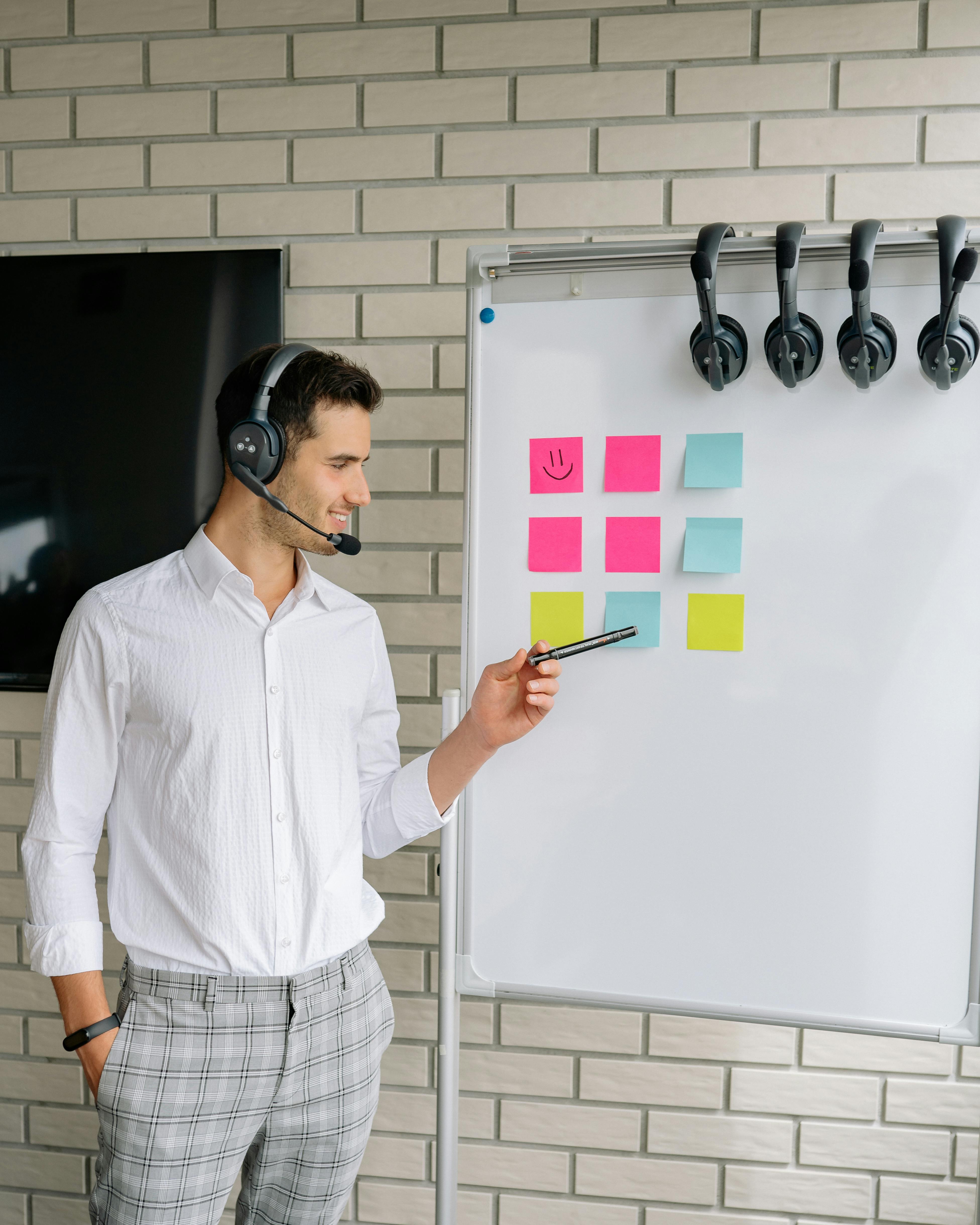 man in white long sleeves wearing headphones pointing marker on sticky notes