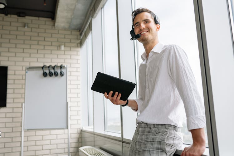 Low-Angle Shot Of A Man In White Long Sleeves Wearing Headphones While Holding A Tablet