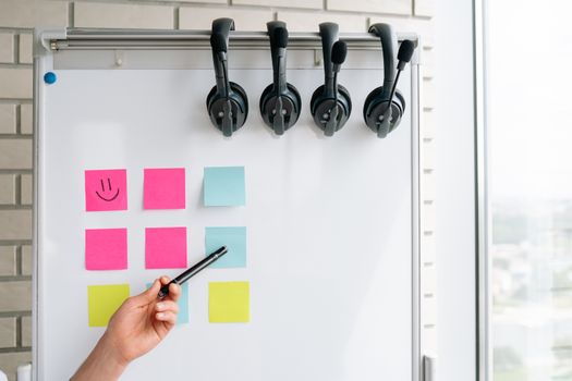 Whiteboard with sticky notes and hung headphones, ideal for office settings.