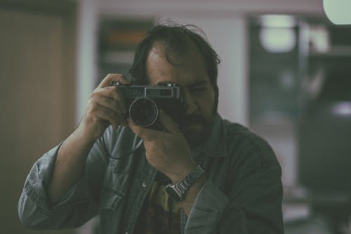 Man in Denim Jacket Holding Black Camera