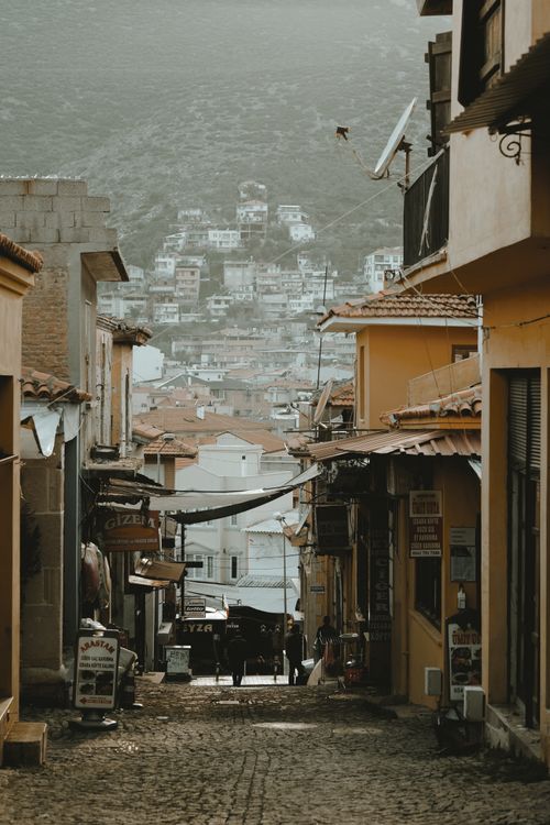Free Quaint narrow street in a historic town lined with warm-colored buildings, perfect for travel lovers. Stock Photo