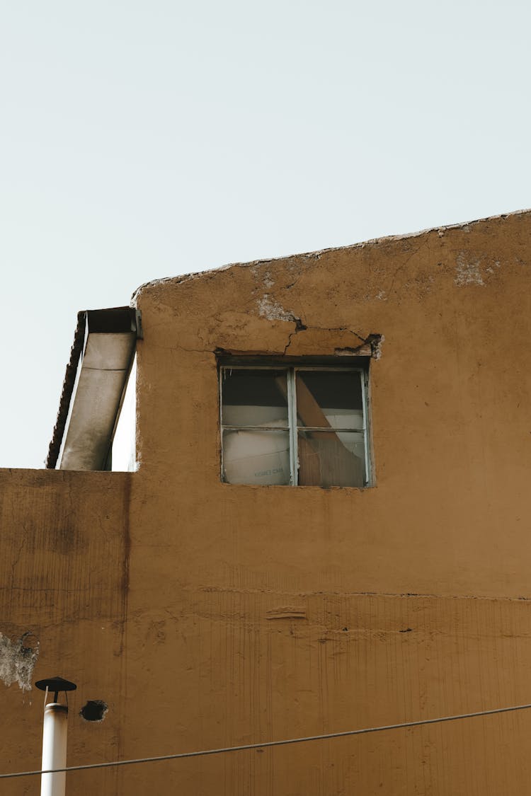 Brown Concrete Building With A Broken Glass Window