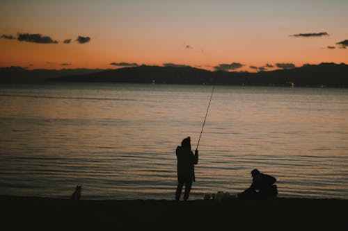 Free Silhouette of Two People Fishing on Sea during Sunset Stock Photo