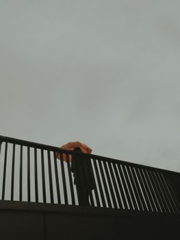 A striking low angle shot of a bridge featuring an orange umbrella against a cloudy sky.