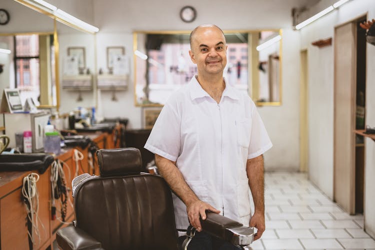 A Barber Holding On The Armrest Of A Barber Chair