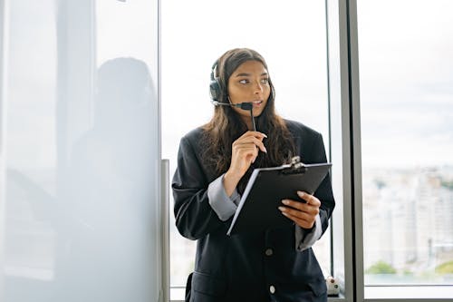 Free A Call Center Agent Working while Leaning by the Window Stock Photo