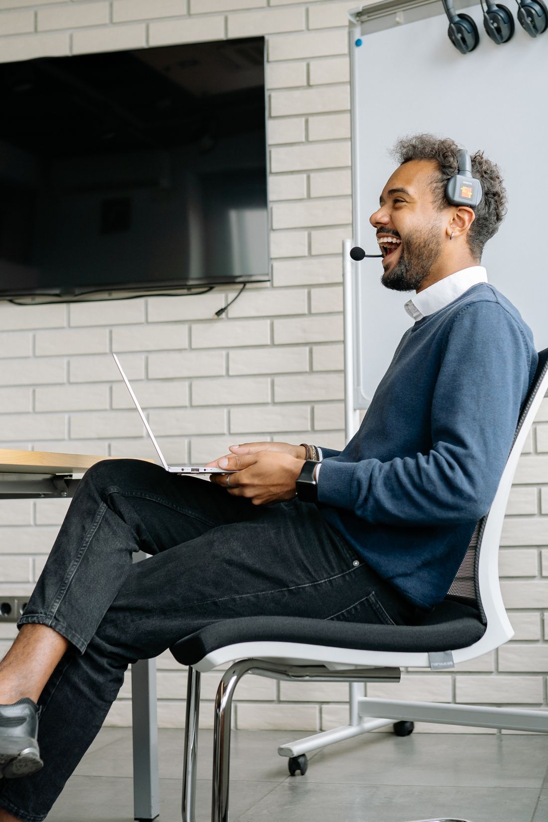 Illustrative photo: a smiling technical support specialist with a headset working on a laptop in a bright office