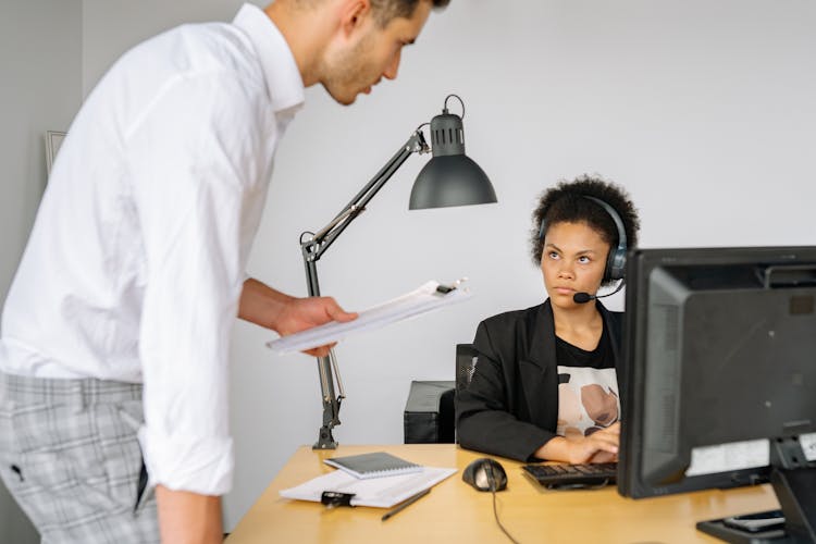 Curly Haired Woman Wearing Headset Staring At The Man In White Long Sleeves