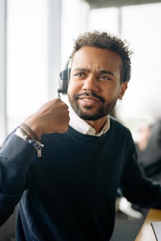 African American man wearing headset, working in a modern office environment.