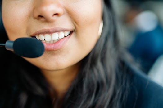 Close-up of a smiling customer service agent wearing a headset in an office environment.