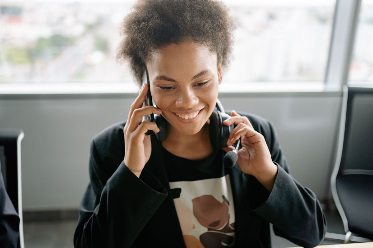 Agenta de call center zambind, vorbind la telefon cu casti cu microfon