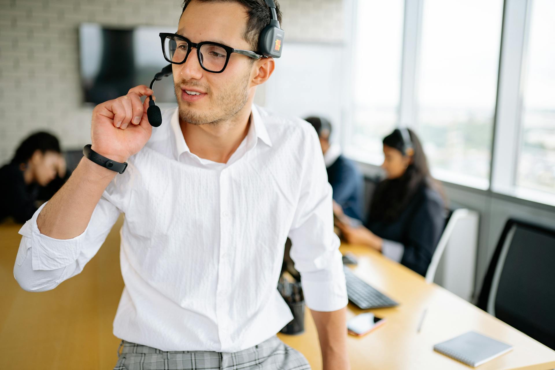 Adult man wearing headset handling business communication in a modern office setting.