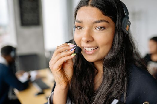 Smiling woman in call center with headset and microphone at office desk.