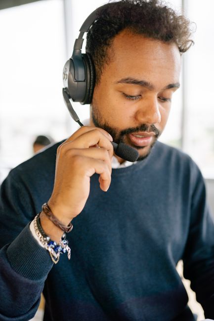 Professional call center agent in an office environment wearing a headset, focused on the conversation. Professional call center agent in an office environment wearing a headset, focused on the conversation.