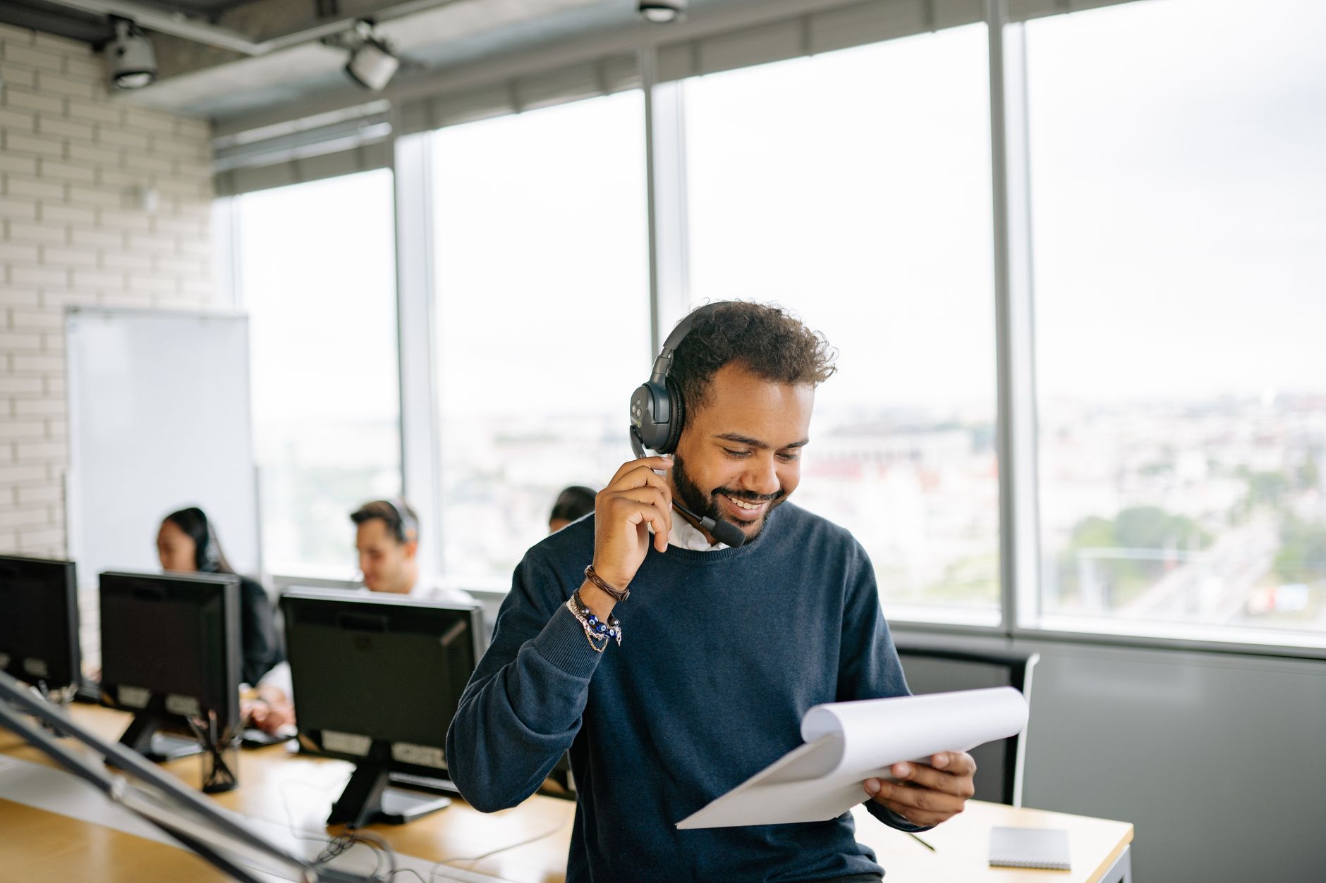 個人品牌服務商品化全攻略:方案設計、範圍定義、交付與SLA Friendly call center agent engaged in conversation while reviewing documents at his desk.