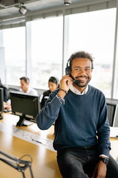 Happy man in headset sitting at desk in modern office, engaging in work.