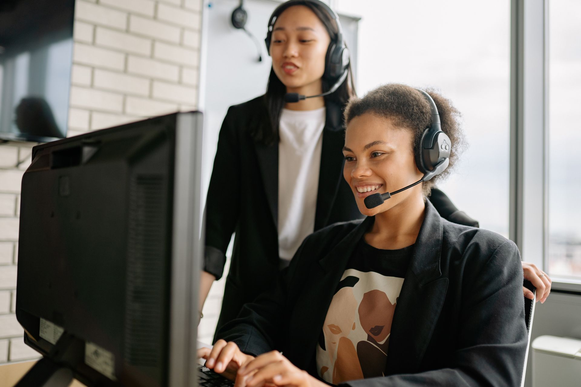 Two agents wearing headsets seated at a desk making calls