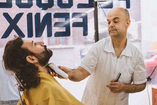 Barber expertly shaving a bearded client in a bustling barbershop.