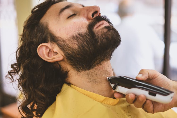 Barber Shaving A Man's Beard With Hair Clipper