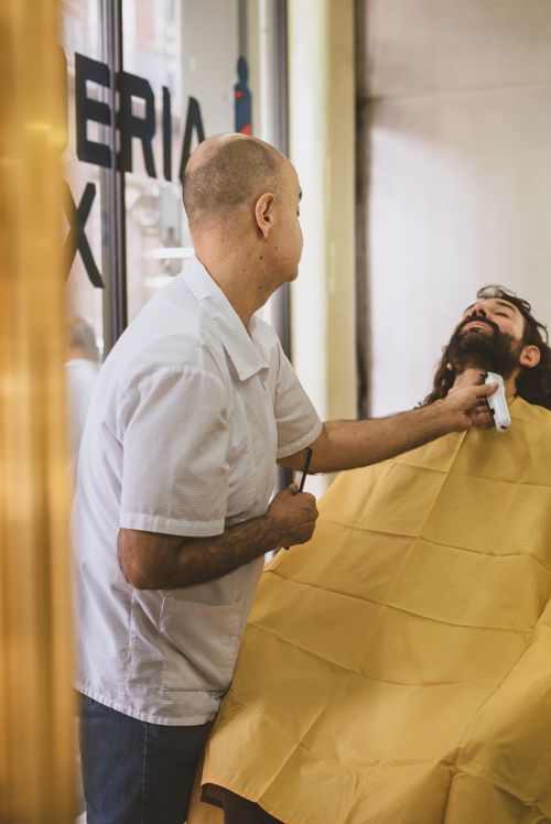 Free Barber providing a close shave to a male client in a classic barber shop setting. Stock Photo
