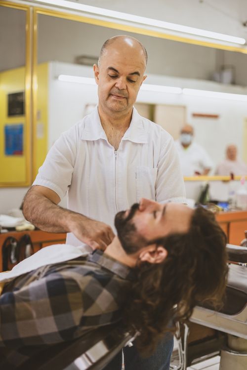Free Barber providing a classic shave to a customer in a traditional barbershop setting. Stock Photo