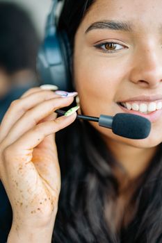 Close-up of a cheerful woman with headphones, engaged in a customer service role.