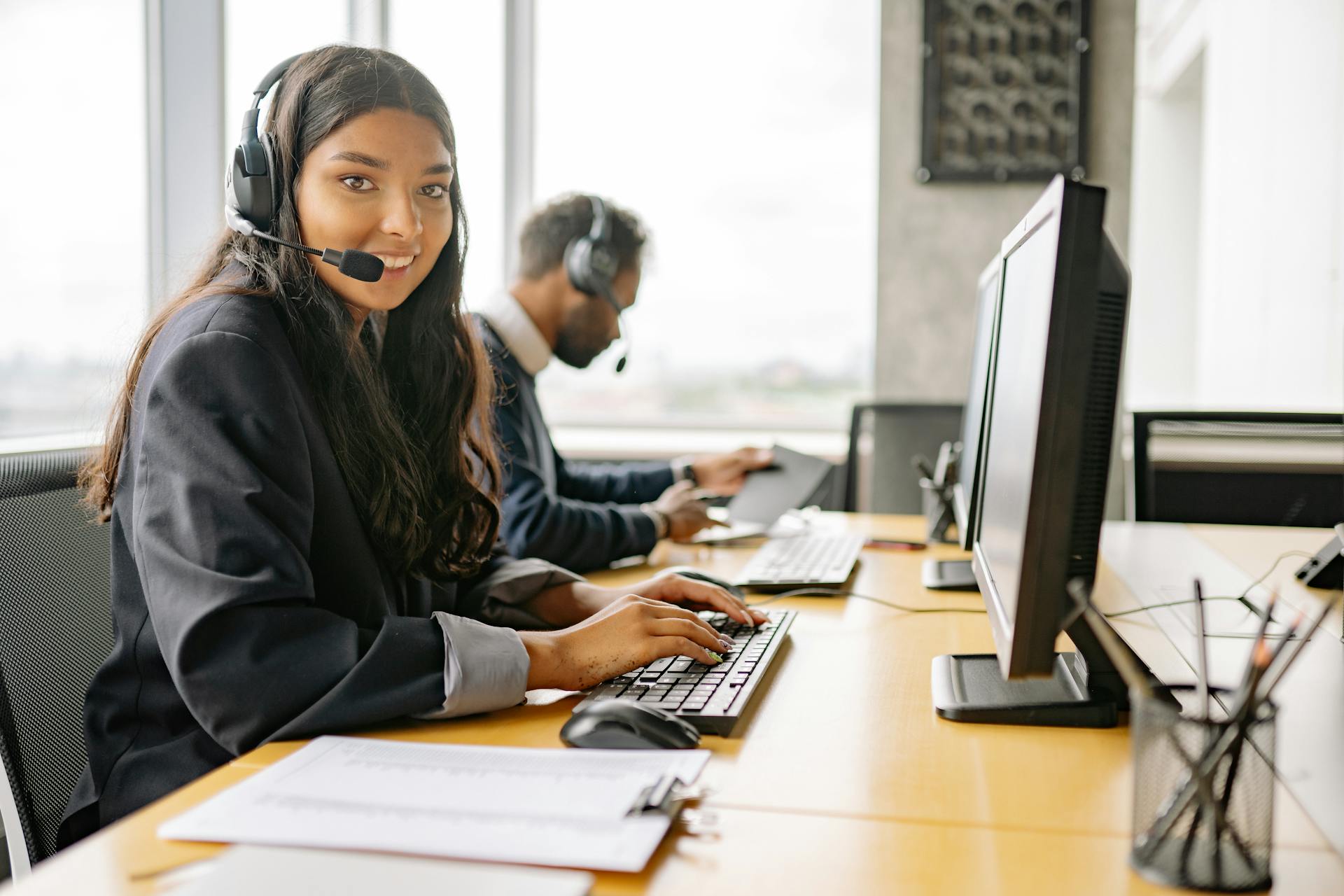 Free A Smiling Woman Working in a Call Center while Looking at Camera Stock Photo