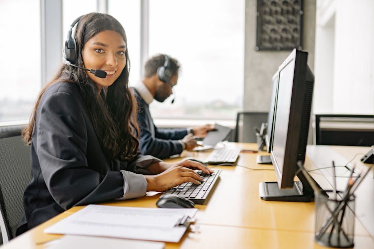 A Smiling Woman Working In A Call Center While Looking At Camera