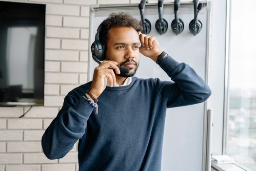 Focused call center agent wearing headphones and a blue sweater, looking away thoughtfully.