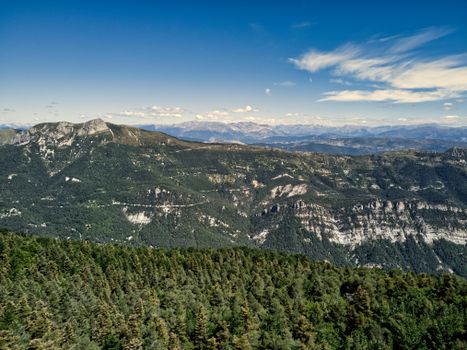 Discover the breathtaking aerial view of a lush green mountain range under a clear blue sky.